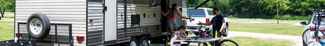 man and 2 women hanging out outside of RV. 